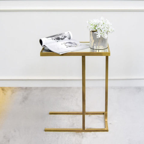 Sleek and clean lined C shaped side table with a muted brushed gold finishing and a mirror top surface for a classy modern look.