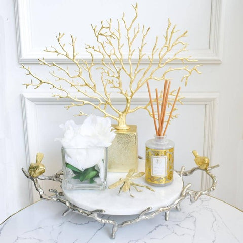 Atelier Marble Decorative Tray with Birds, Round, on display with Dragonfly insect sculpture and Reed diffuser and La Prosperite brass coral sculpture.