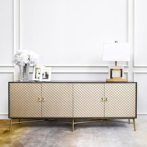 Modern Art Deco style TV console in hand-painted door panels in varying champagne-gold mixed hues and intensities. Decorated with white flowers in glass vase, photo frames and table lamp.